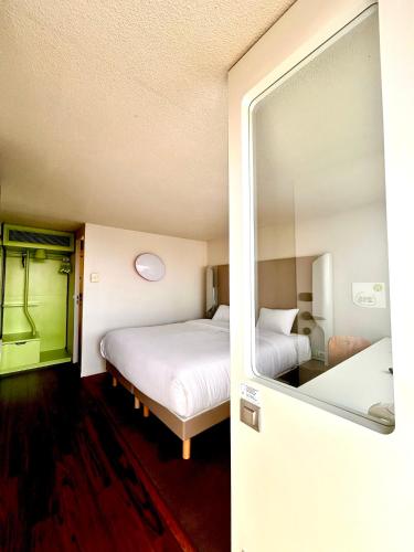 a hotel room with two beds and a mirror at Campanile Montargis - Amilly in Amilly