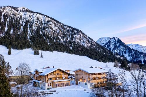 a house in the snow with mountains in the background at Hotel Kühberg in Oberstdorf
