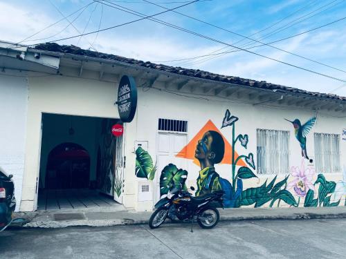 a motorcycle parked in front of a building with a mural at Hotel Casa Corleone in Garzón
