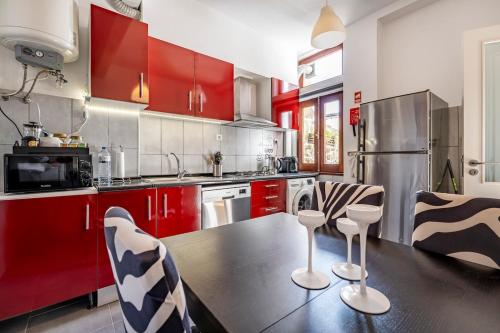 a kitchen with red cabinets and a table and chairs at Casa da Foz in Porto