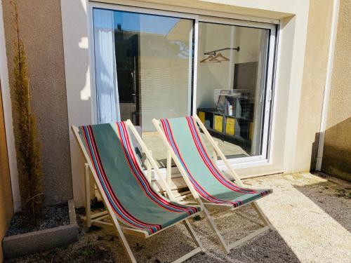 two lawn chairs sitting in front of a window at Le studio de Marie in Noves