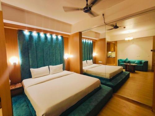 a hotel room with two beds and a couch at The Grace Residency - Gomtinagar, Lucknow in Lucknow