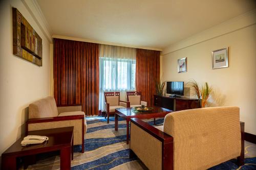 a hotel room with a table and chairs and a television at Lancaster Kumasi City in Kumasi