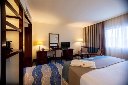 a hotel room with a bed and a desk at Lancaster Kumasi City in Kumasi