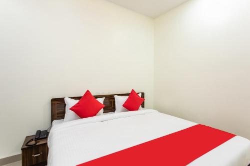a bedroom with a white bed with red pillows at Hotel O Manjulam Regency in Indore