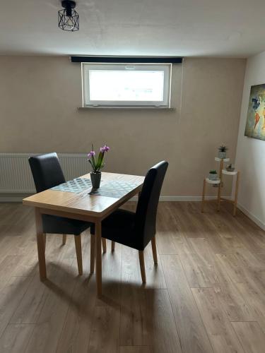 a dining room table with chairs and a vase of flowers on it at Chez Nadia in Leutenheim