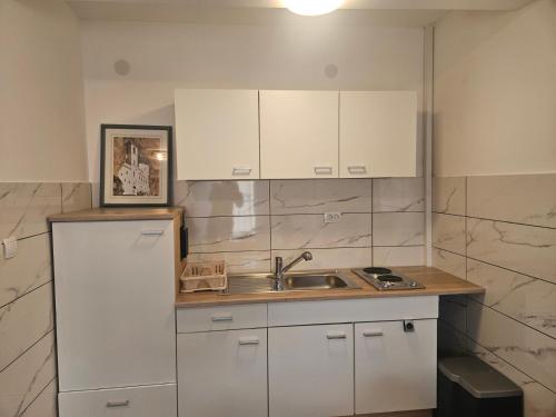 a kitchen with white cabinets and a sink at MIRO Apartmani in Pale