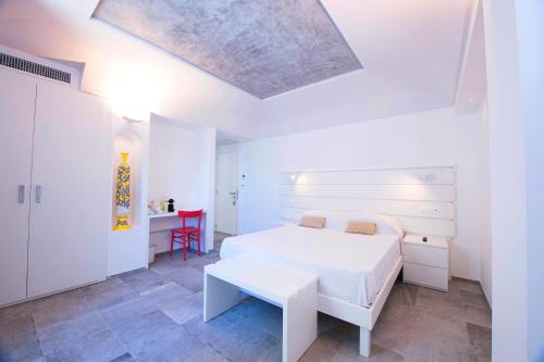 a white bedroom with a white bed and a table at Villa Bossa Amalfi in Amalfi
