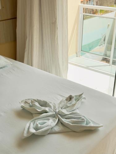 a white bow on a white bed with a window at Hotel Costa do Delta in Tutóia