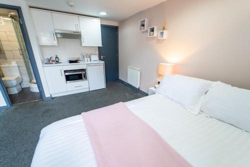 a bedroom with a large white bed and a kitchen at 24 Dale Road Studios in Birmingham