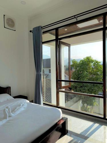 Un dormitorio con una cama y una ventana grande. en Utopia house-luang prabang琅勃拉邦乌托邦庭院, en Luang Prabang