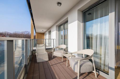 a balcony with chairs and tables on a building at Rezydencja Merwede Aparthotel - My Rest in Gdańsk