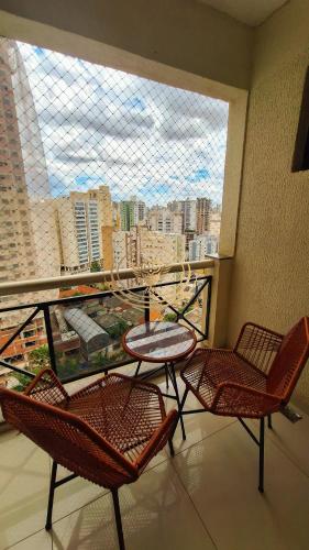 a balcony with two chairs and a table and a window at Coruja Imob - Flat Crystal Place in Goiânia