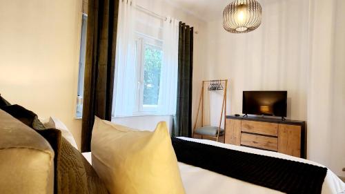 une chambre avec un lit, une télévision et une fenêtre dans l'établissement L'Atelier d'Antoine, à Longeville-lès-Metz