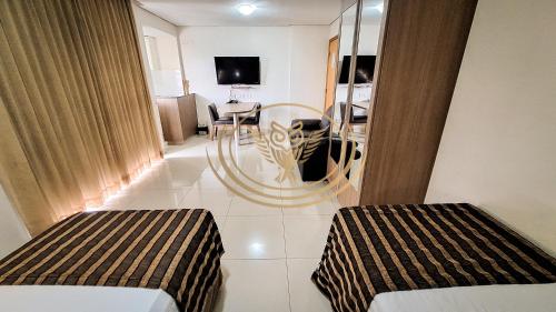 a room with two beds and a dining room at Coruja Imob - Flat Crystal Place in Goiânia