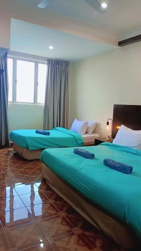 two beds in a room with blue sheets on them at Jev Penthouse in Port Dickson