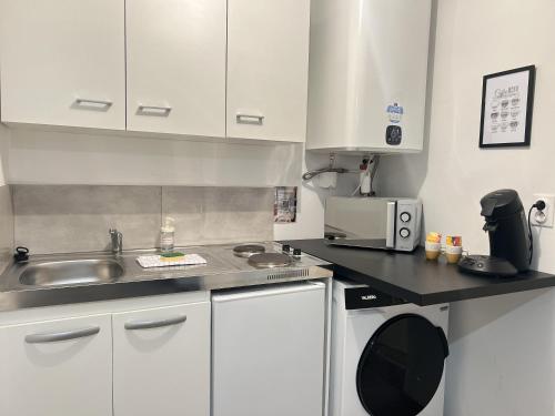 une cuisine avec des armoires blanches, un évier et un micro-ondes dans l'établissement La Place, à Calais