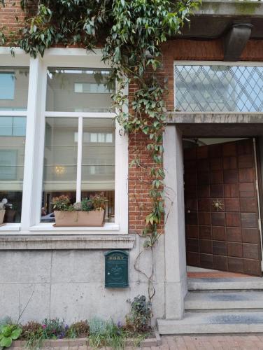 a building with two windows and two potted plants at B&B l'Inconnu in Roeselare