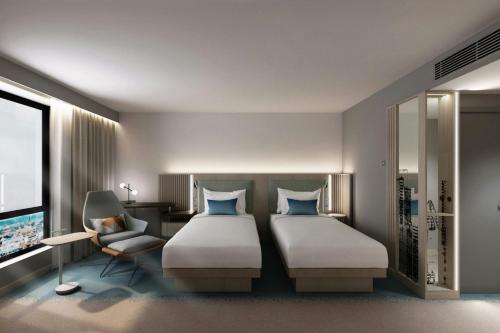 a bedroom with two beds and a chair and a television at Courtyard by Marriott Sheffield in Sheffield