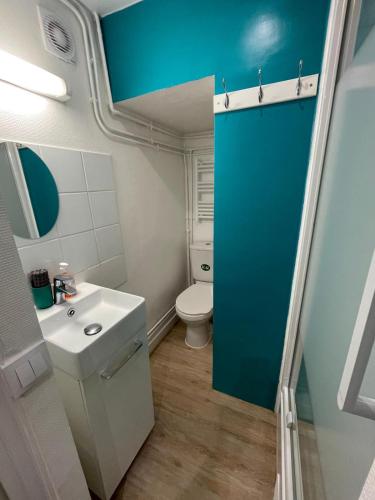 La salle de bains est pourvue de toilettes blanches et d'une porte bleue. dans l'établissement Paris Arts et Métiers, à Paris