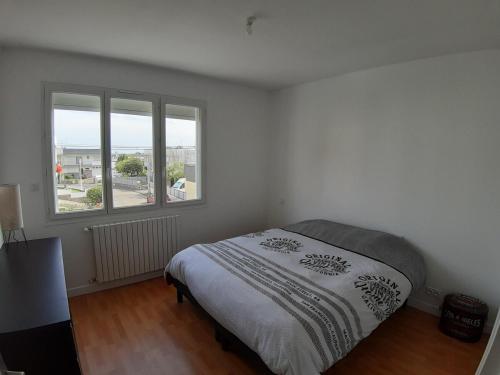 une chambre blanche avec un lit et deux fenêtres dans l'établissement Maison de 70 m2 Quartier Manio, à Lorient