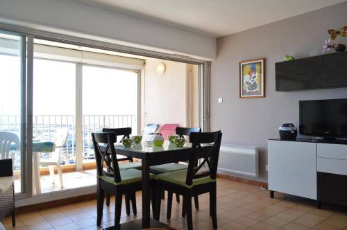 une salle à manger avec une table avec des chaises et une télévision dans l'établissement 2 pièces belle vue mer CAP D 'AGDE CT360-435, au Cap d'Agde