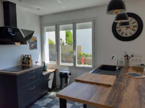 une cuisine avec une horloge sur le mur et une table dans l'établissement Maison de 70 m2 Quartier Manio, à Lorient