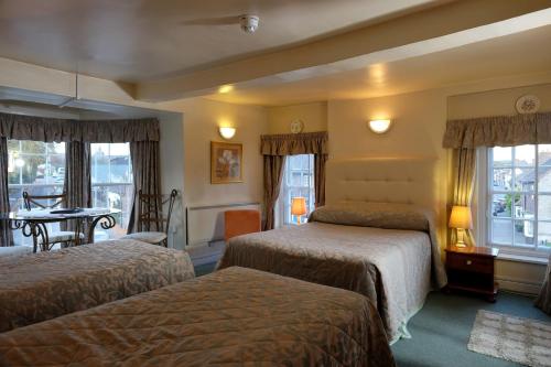 a hotel room with two beds and a table at Gaskell Arms in Much Wenlock