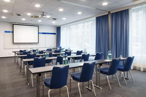a conference room with tables and chairs and a screen at Park Inn by Radisson Frankfurt Airport in Frankfurt/Main