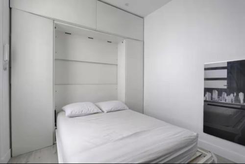 Cette chambre blanche dispose d'un lit et d'une télévision. dans l'établissement Fantin Latour studio confortable 2P Seine et tour Eiffel, à Paris