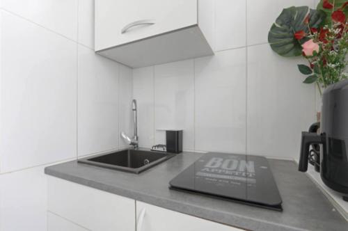 une cuisine avec un évier et un ordinateur portable sur un comptoir dans l'établissement Fantin Latour studio confortable 2P Seine et tour Eiffel, à Paris