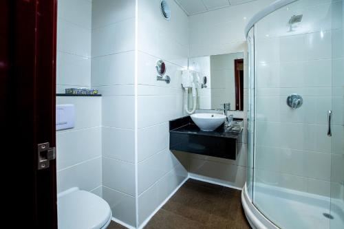 a bathroom with a toilet and a sink and a shower at Lancaster Kumasi City in Kumasi