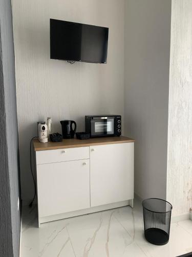 a microwave on a white cabinet with a tv on the wall at A Casa di JO in Bari