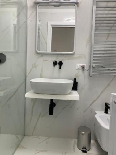 a white bathroom with a sink and a mirror at A Casa di JO in Bari