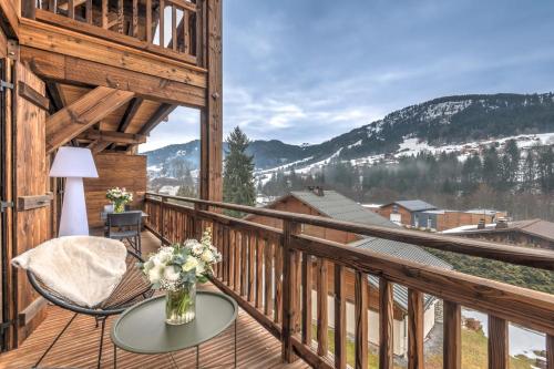 - un balcon avec une table, une chaise et un vase de fleurs dans l'établissement Chalet Emy - Welkeys, à Praz-sur-Arly