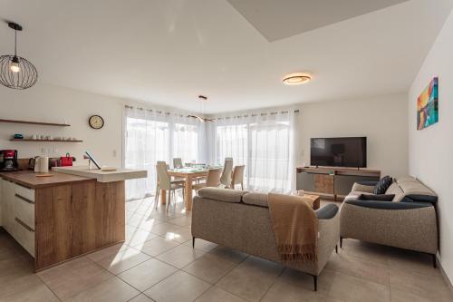 une cuisine et un salon avec une table et des chaises dans l'établissement Villa Kaino 1 - Climatisée avec jardin, à Ondres