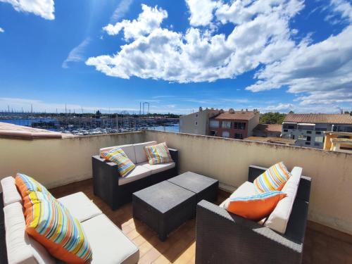 d'un balcon avec des canapés et des tables sur le toit. dans l'établissement Cap d'Agde Vue Port et Mer Parking Terrasse la Désirade, au Cap d'Agde