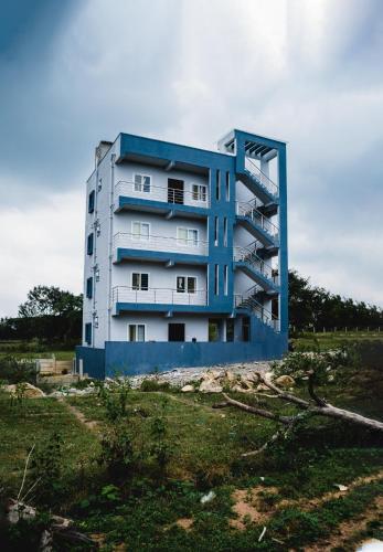 a blue and white building in the middle of a field at Vivaan Comforts in Bidadi