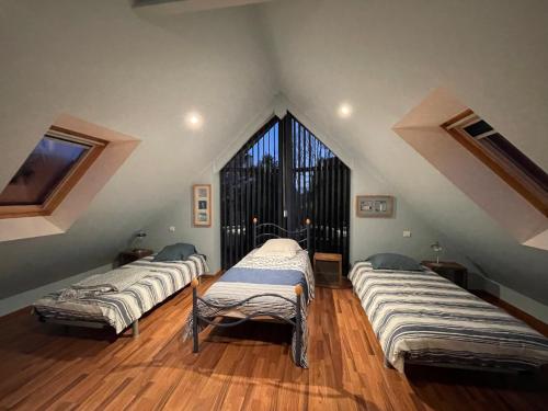 three beds in a room with a large window at Jolie maison de vacances avec une vue magnifique sur le jardin in Combrit