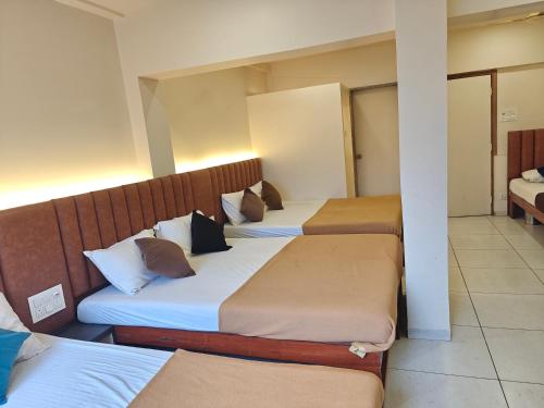 a room with three beds in a hotel room at Central Inn, Kolhapur in Kolhapur