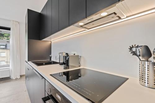a kitchen with black and white cabinets and a sink at Modern Apartments in Clausen with WiFi, Kitchen & Workspace in Luxembourg