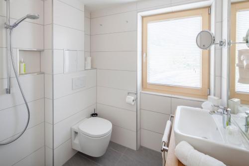 a white bathroom with a toilet and a sink at Bio-Berghotel Ifenblick in Balderschwang