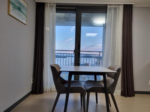 a table and chairs in a room with a window at Yeosu UTOP UBLESS All Rooms Stunning Ocean View in Yeosu