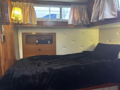 a bedroom with a bed and a tv on a boat at Floating tranquility in Dorney