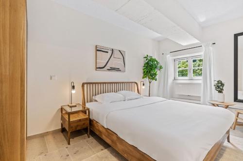 a white bedroom with a large bed and a window at Modern Apartments in Clausen with WiFi, Kitchen & Workspace in Luxembourg