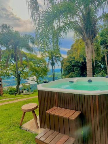 a hot tub with a bench next to a tree at Sitio mirante do Lopo in Vargem