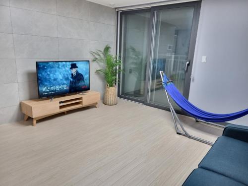 a living room with a flat screen tv and a blue hammock at Yeosu UTOP UBLESS All Rooms Stunning Ocean View in Yeosu