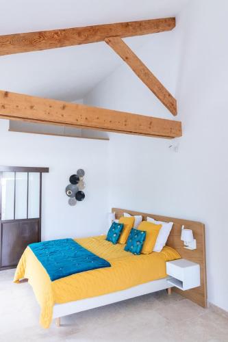 - une chambre avec un lit doté d'oreillers jaunes et bleus dans l'établissement Mas des Tourterelles, à Jonquières