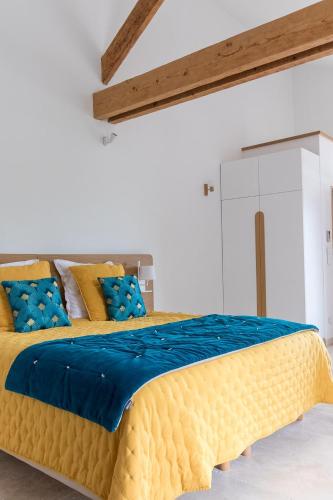 - une chambre avec un grand lit jaune et des oreillers bleus dans l'établissement Mas des Tourterelles, à Jonquières