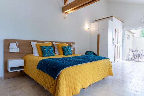 - une chambre avec un grand lit jaune et des oreillers bleus dans l'établissement Mas des Tourterelles, à Jonquières